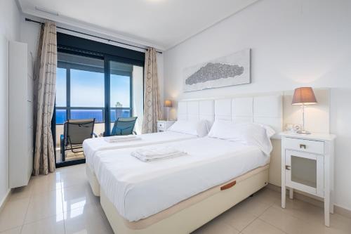 贝尼多姆Gemelos 26 Resort Apartment 27C Levante Beach的一间白色卧室,配有床和阳台