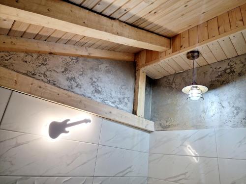 Bistriţa BîrgăuluiVila N&N Palace的浴室设有淋浴,墙上有吉他影子