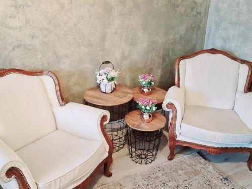 Bistriţa BîrgăuluiVila N&N Palace的两把白色的椅子和一张带鲜花的桌子
