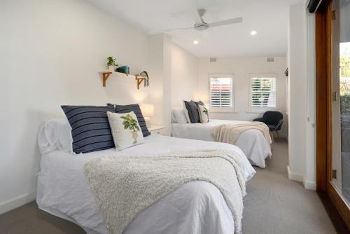 悉尼Beach Retreat的白色墙壁客房的两张床