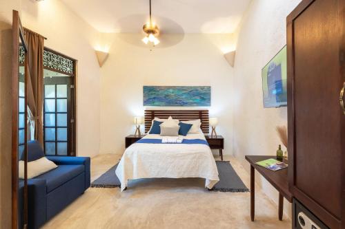 梅里达Casa Dos Lirios Hotel Boutique的一间卧室配有一张床和一张蓝色的沙发