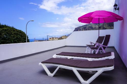 洛西洛斯Casa Ángela, Canarian Heritage的阳台上配有两把椅子和一把粉红色的遮阳伞