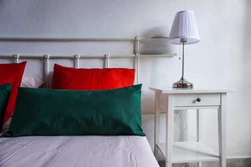 洛西洛斯Casa Ángela, Canarian Heritage的一张带红色和绿色枕头的床,旁边是桌子