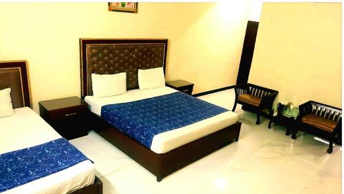 卡拉奇Hotel Sky Inn Gulsan的一间卧室配有两张床和两把椅子