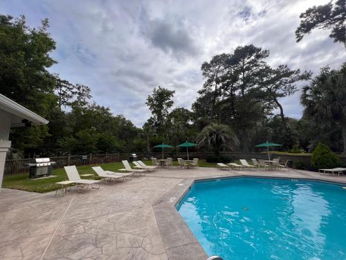 希尔顿黑德岛3 BR Villa Perfect for Families and Friends in Sea Pines, Hilton Head的一个带躺椅和遮阳伞的游泳池