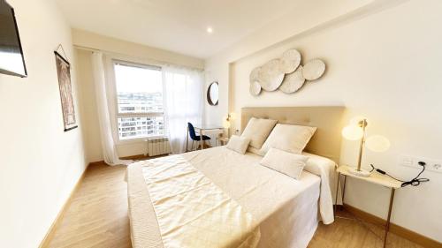 圣塞瓦斯蒂安Paradise Luxurious flat, free parking, 3 double rooms, terrace, jacuzzi, fully renovated的白色的卧室设有一张大床和一个窗户