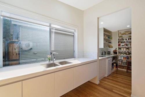 梅林布拉Sea Change and Studio on Tasman的白色的厨房设有水槽和窗户