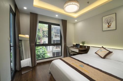 河内Bao Hung Hotel & Apartment - Tran Quoc Vuong的卧室配有一张床、一张书桌和窗户。