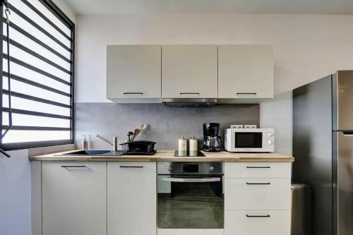 圣勒Leu Burgot 1, Appartement 13的厨房配有白色橱柜和微波炉