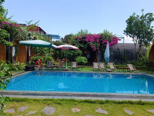 宁平Tam Coc Village Bungalow的庭院内带椅子和遮阳伞的游泳池