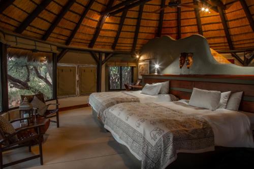 奥奇瓦龙戈Okonjima Luxury Bush Camp的一间带两张床的卧室,位于带窗户的房间内