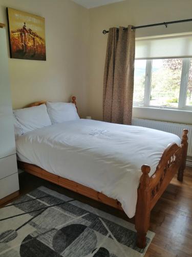 新罗斯An Cúinín的卧室配有一张带白色床单的大床和窗户。