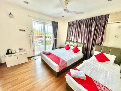 哥打京那巴鲁Borneo Inn的一间卧室配有两张带红色枕头的床