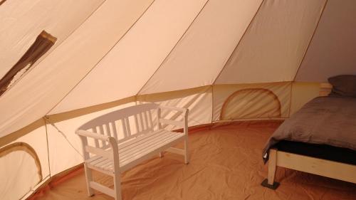 斯泰厄Cosy Farmhouse Glamping的帐篷内的白色长凳和床