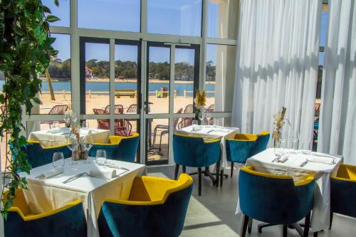 奥瑟戈尔Hôtel du Parc & Spa的一间设有桌椅的餐厅,享有海滩美景