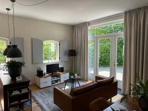 TynaarloKoetshuys van Villadelfia的带沙发的客厅和部分窗户。