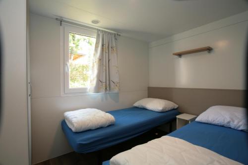 乌马格Camping Adria Mobile Home Park Umag的小房间设有两张床和窗户