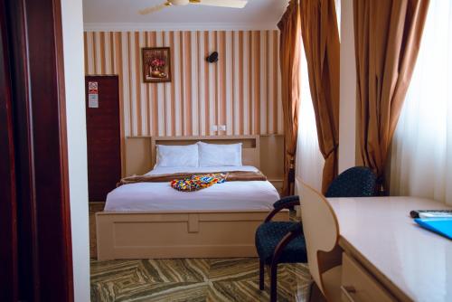 KwedonuExotic Palace Hotel的酒店客房,配有一张床、一张桌子和椅子