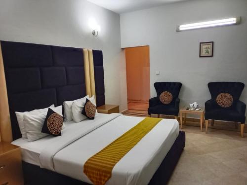 伊斯兰堡Capri Residency的一间卧室配有一张大床和两把椅子