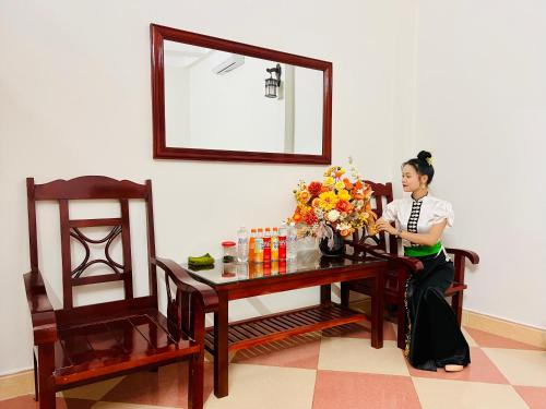 Ban Hin LomNhà nghỉ Xuân Long - Xuan Long gues - Tỉnh Điện Biên的坐在桌子上,花瓶的女人