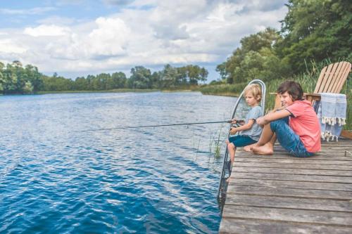 BrzozieLunette Lodge am See mit Sauna für 10 Gäste的两个孩子坐在码头上,在湖上钓鱼