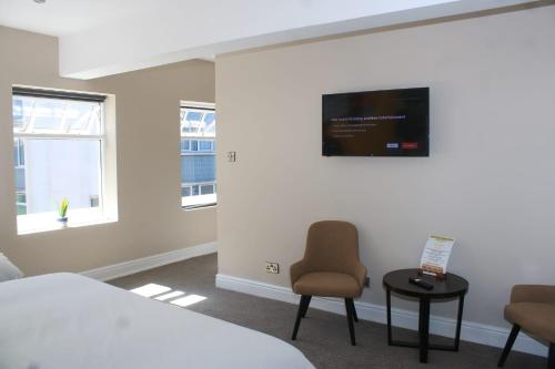 利物浦Fenwick Sunrise Hotel的卧室配有一张床,墙上配有电视。
