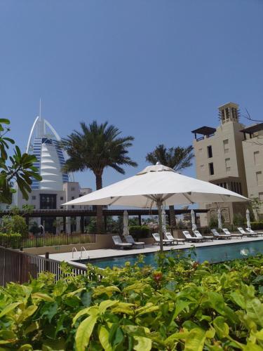 迪拜Ultimate Stay / Next to Burj Al Arab / Upscale Luxury / Amazing Pool with a View / Perfect Holiday / Madinat Jumeirah / 2 BDR的一个带椅子和遮阳伞的游泳池以及建筑