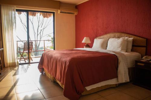 埃尔莱马特Camino Real Tikal‎的一间卧室设有一张红色墙壁和窗户的床