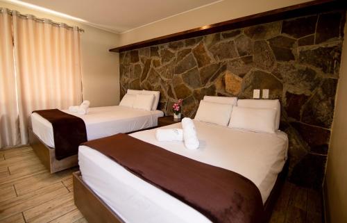 谢内吉亚区Hotel Campo & Leña的酒店客房设有两张床和石墙。