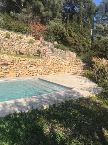 土伦Hauteurs de Toulon : Charmant studio piscine的石墙旁边的游泳池