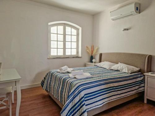 法鲁Qta do Eucalipto Villa的一间卧室配有一张带条纹毯子的床和窗户
