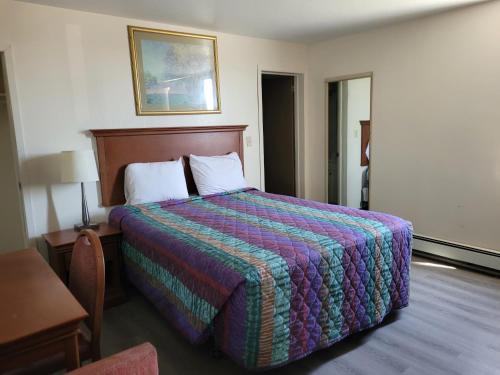 萨德伯里Canadiana Motel的酒店客房设有一张大床和色彩缤纷的毯子