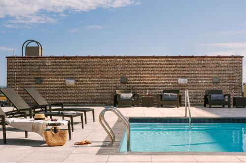 新奥尔良Sonder at 1500 Canal的砖墙旁的游泳池配有桌椅