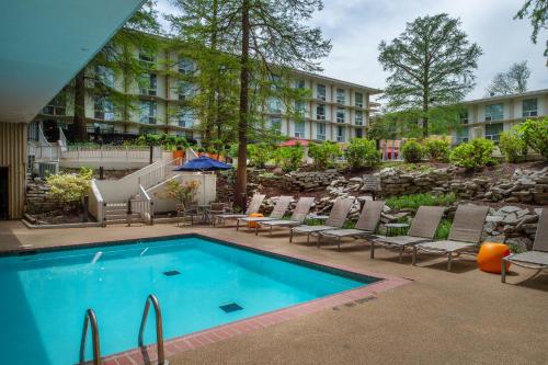 埃德蒙逊马里奥特酒店圣路易斯机场店的一个带椅子的游泳池,以及一间位于酒店后面的酒店