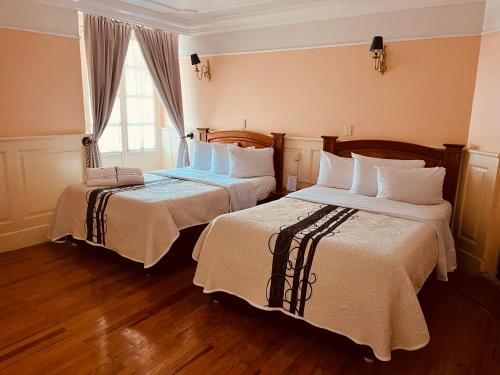 米内拉尔德尔蒙特Hotel Real Del Monte的酒店客房设有两张床和窗户。
