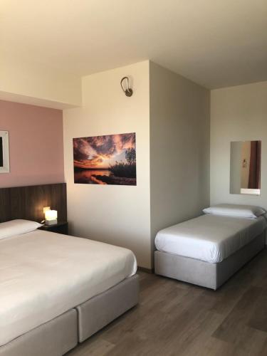 Bagnolo PiemontePrealpina Hotel的一间卧室设有两张床,墙上挂着一幅画