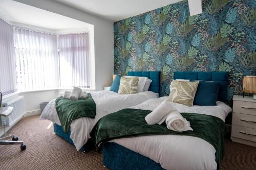 伯明翰Heartland House, 7 Spacious Bedrooms Sleeps 4 plus, near NEC, JLR,BHX的卧室内的两张床,配有蓝色和绿色的壁纸