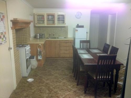WinkieMigga Cottage的厨房配有桌椅和冰箱。