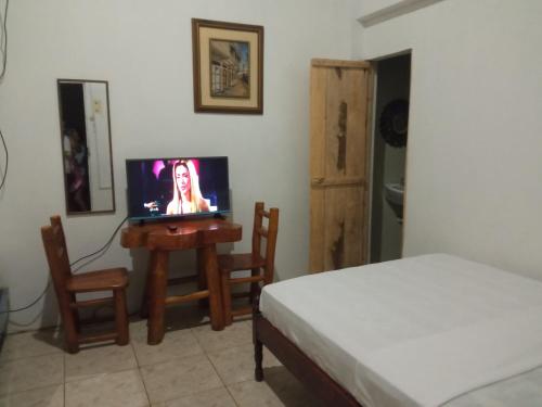 圣埃莱纳Hospederia Oasis的一间卧室配有一张床和一张桌子上的电视