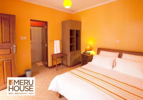 NkubuThe Meru House的一间卧室设有一张床和黄色的墙壁