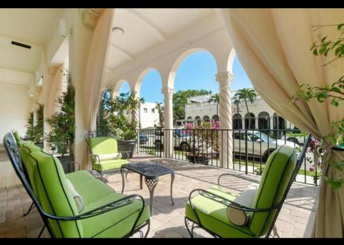 棕榈滩Tropical Palm Beach 2 Bedroom 2 Bathroom Suite POOL -BEACH 2 Blocks Valet Parking Included的阳台设有带绿色椅子和桌子的庭院