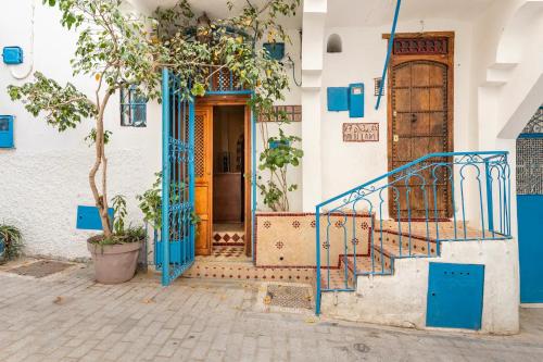 丹吉尔Dar Sandra Moroccan Tiny House的一座拥有蓝色门和楼梯的建筑