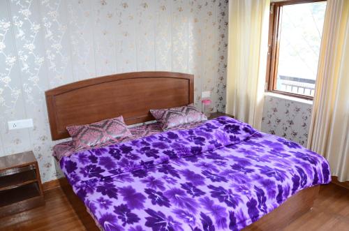 穆索里Bhandari Homestay and Restaurant的卧室床上的紫色棉被