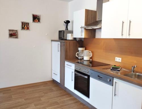 ReinhardtsdorfFerienwohnung Berger的厨房配有白色橱柜和水槽