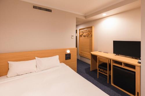 东京Sotetsu Fresa Inn Tokyo-Akasaka的酒店客房配有一张床和一张书桌及一台电视