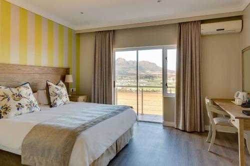 斯泰伦博斯Protea Hotel by Marriott Stellenbosch & Conference Centre的一间卧室配有一张床、一张书桌和一个窗户。