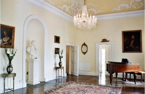赫里福德Newcourt Manor的客厅配有钢琴和吊灯