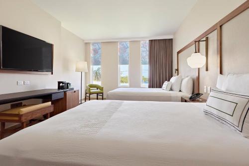 坎昆Fairfield Inn & Suites by Marriott Cancun Airport的酒店客房设有一张大床、书桌和电视。