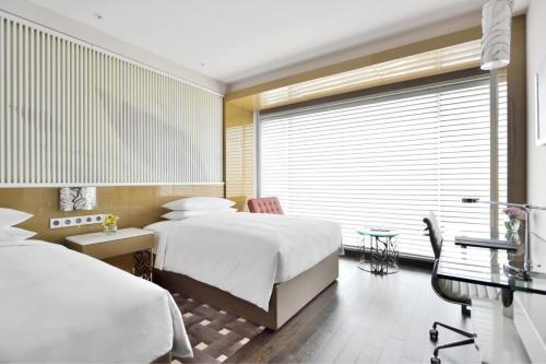 勒克瑙勒克瑙万丽酒店的一间卧室设有两张床、一张桌子和一个窗口。