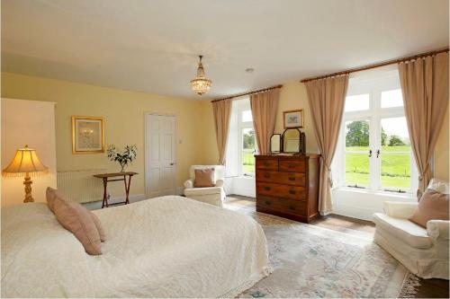 赫里福德Newcourt Manor的一间卧室配有一张床、一把椅子和窗户。